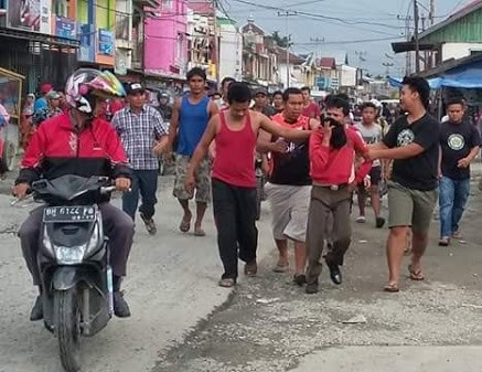 RK (baju merah lengan panjang) saat digelandang warga ke pos polisi.
